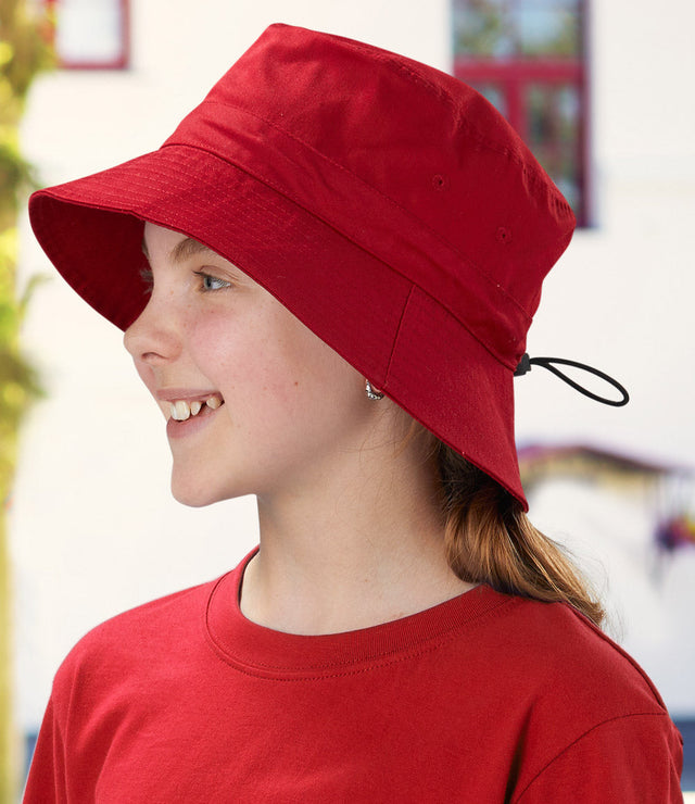 Smiling child wearing a bright red bucket hat with drawcord and matching T-shirt – ideal for custom school hats, sun-safe uniforms, and eco-friendly headwear options in Australia.