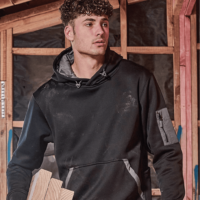 Young tradesman wearing black work hoodie with utility pocket – custom printed jumper with free logo included, ideal for construction and job sites.