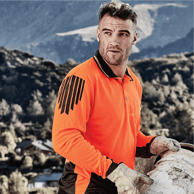 Construction worker wearing long sleeve hi-vis orange and black polo shirt on job site – custom safety workwear with free logo included.