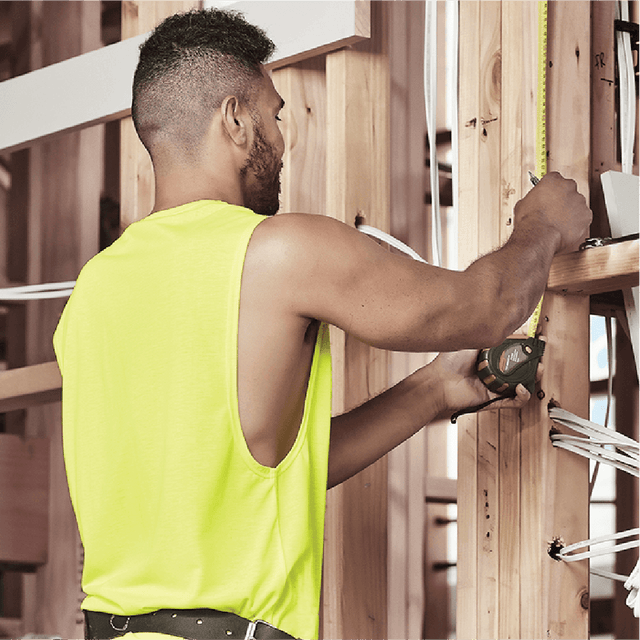 Male tradie wearing hi-vis yellow safety singlet on construction site – lightweight custom singlet with free printed logo included.