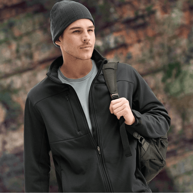 **Alt Text:** Man wearing black softshell work jacket and beanie outdoors – custom printed jacket with free logo included, perfect for staff uniforms and winter workwear.