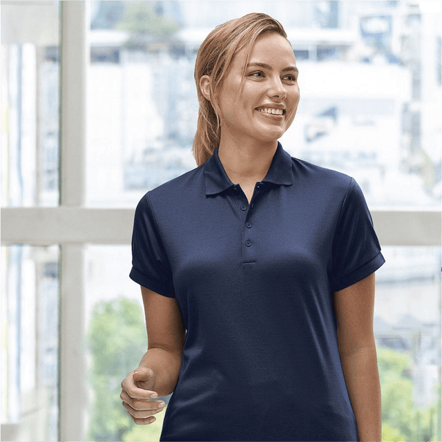 **Alt Text:** Smiling woman wearing navy custom polo shirt – personalised uniform with free printed logo included, ideal for workwear and team branding.