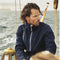 **Alt Text:** Man wearing navy custom sports jacket on a boat in wet weather – water-resistant teamwear with free logo included, ideal for clubs, events, and outdoor activities.