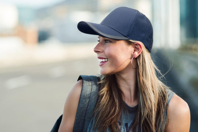 Smiling woman wearing a navy performance cap with mesh side panels – ideal for custom branded caps for clubs, events, and activewear promotions in Australia.