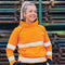 **Alt Text:** Female worker wearing orange hi-vis fleece jumper with reflective tape – custom safety hoodie with free printed logo included, ideal for cold worksites.