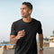 **Alt Text:** Man running along the beach wearing black custom T-shirt – personalised activewear with free logo included, perfect for events, teams, and casual uniforms.