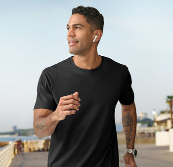 **Alt Text:** Man running along the beach wearing black custom T-shirt – personalised activewear with free logo included, perfect for events, teams, and casual uniforms.