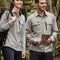 Man and woman walking outdoors in custom grey long-sleeve work shirts and navy shorts – ideal for custom branded work shirts with no minimum order, designed for tradies and outdoor teams in Australia.