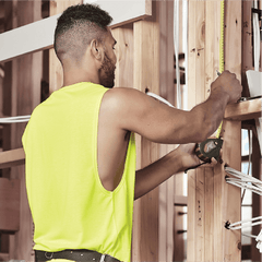 Male tradie wearing hi-vis yellow safety singlet on construction site – lightweight custom singlet with free printed logo included.