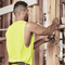 Male tradie wearing hi-vis yellow safety singlet on construction site – lightweight custom singlet with free printed logo included.