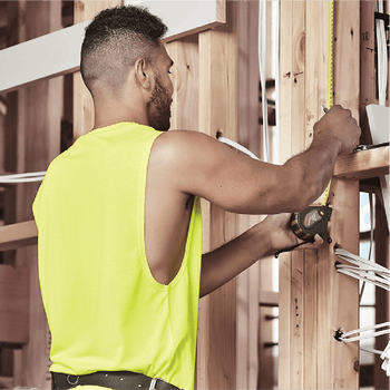 Male tradie wearing hi-vis yellow safety singlet on construction site – lightweight custom singlet with free printed logo included.