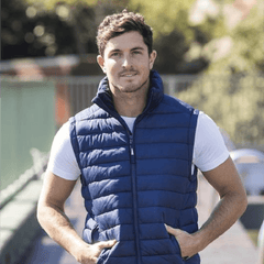 **Alt Text:** Man wearing royal blue custom puffer vest outdoors – personalised corporate vest with free logo included, ideal for staff uniforms and business branding.