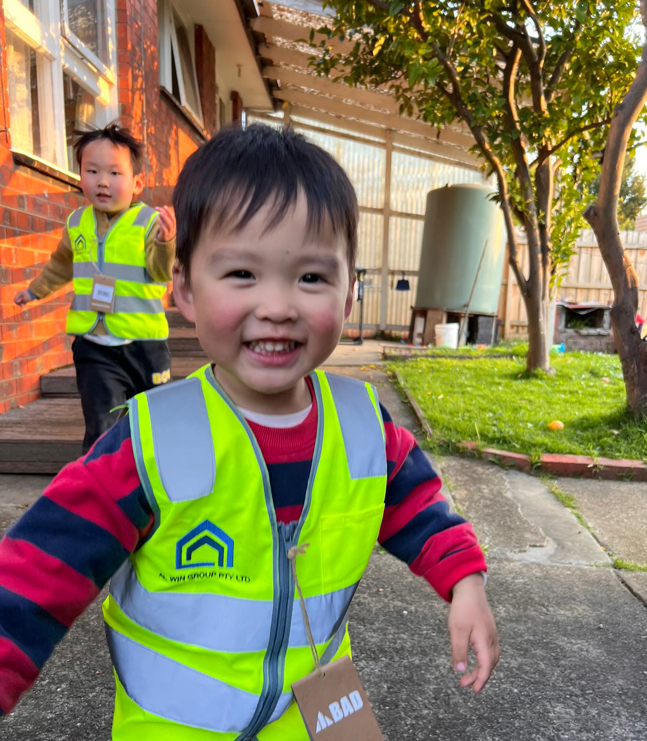 Two young children happily wearing custom hi-vis safety vests outdoors, branded with company logos. A playful yet powerful reminder of the next generation, captured by My Uniform Shop—Australia’s trusted provider of high-quality custom safety gear and branded workwear for businesses big and small. Proudly serving clients nationwide from our family-owned base in Huntingdale, Victoria.